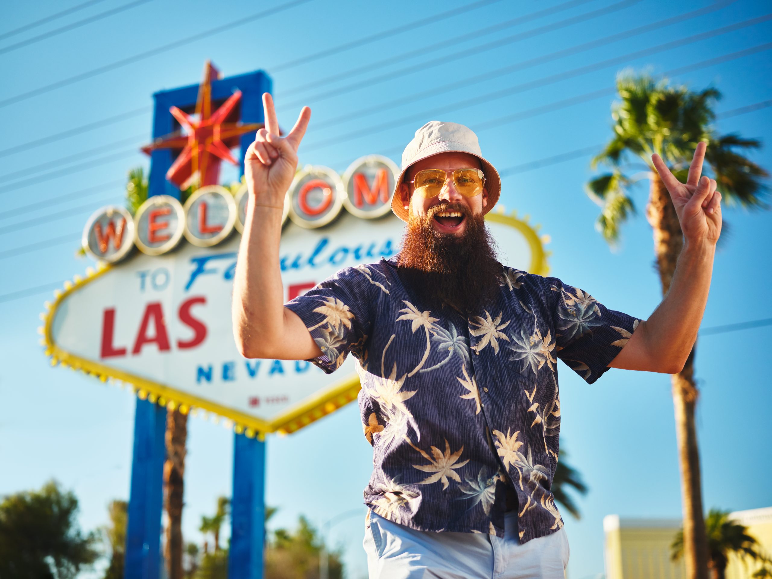 retro tourist making peace sign in front of welcome to las vegas sign